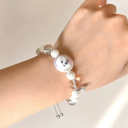 Custom hand-painted pet portrait bracelet featuring a white Bichon Frise dog charm, elegant pearl beads with an adjustable slider chain.