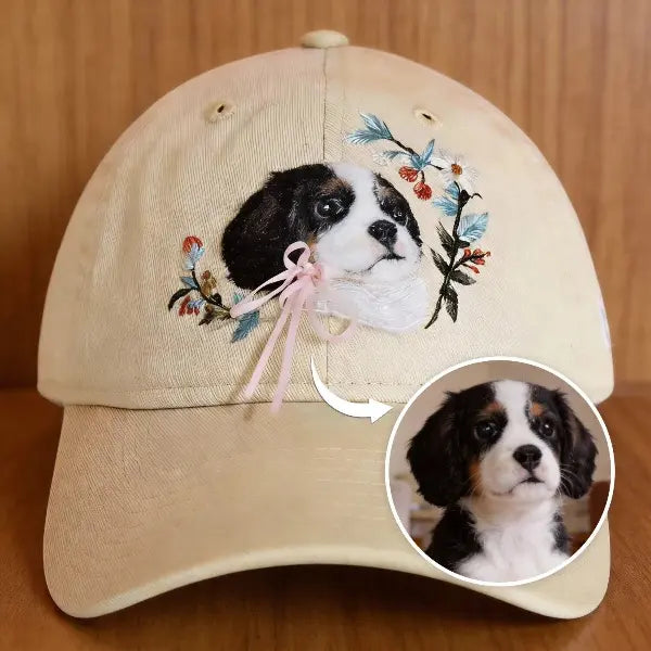 Custom pet photo to hat comparison, showing a real tricolor Cavalier King Charles Spaniel dog photo transformed into a handmade 3D needle-felted portrait on a beige baseball cap with flowers and a pink ribbon bow.