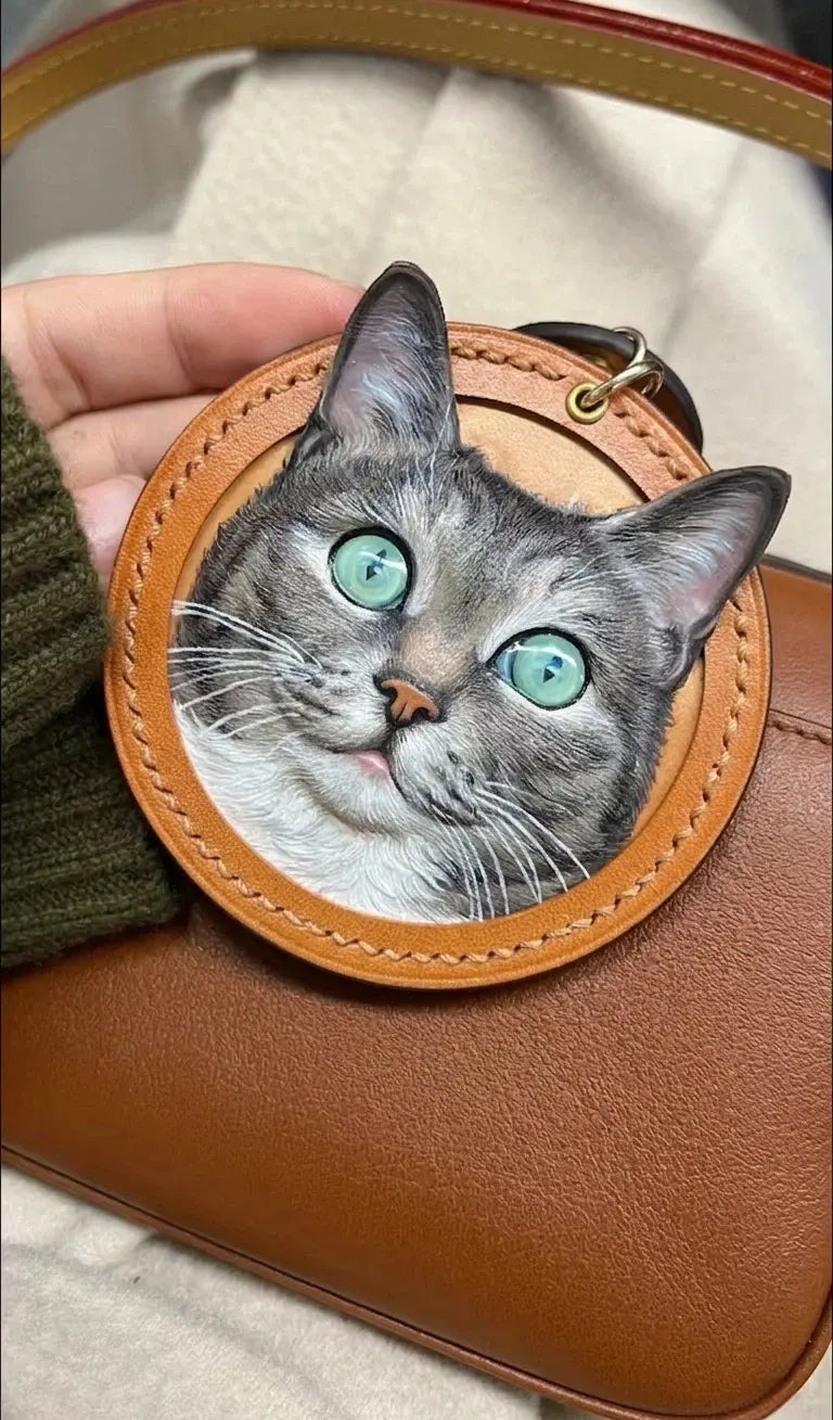 Hand-carved 3D leather silver tabby cat portrait charm with green eyes on a luxury leather handbag, bespoke pet lover luxury accessory by Muse & Paw.