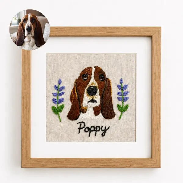 Custom dog photo to embroidery art in a wooden frame, featuring a realistic stitched portrait of a Basset Hound named Poppy with sad hound eyes, long floppy ears, and embroidered purple lavender flowers.