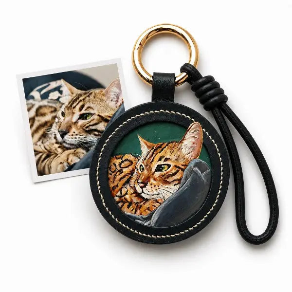 Custom cat photo to leather jewelry comparison, showing a real spotted Bengal cat photo transformed into a hand-painted miniature portrait on a round black leather keychain with a green background.