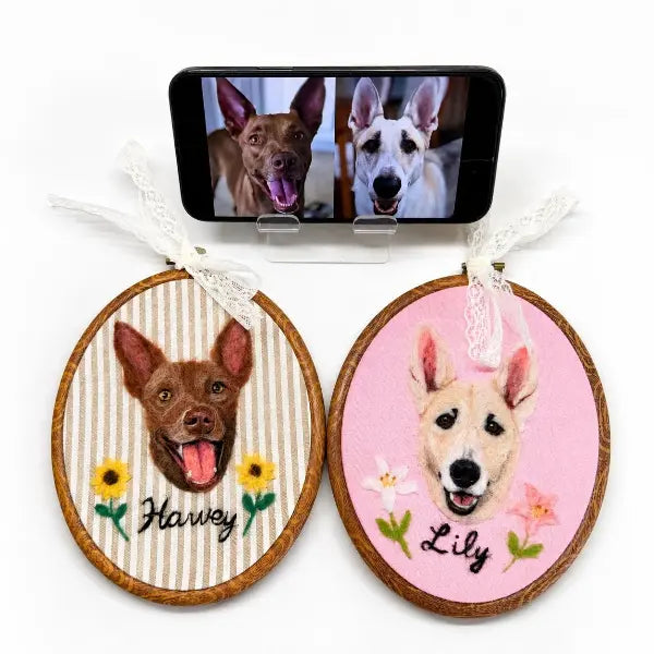 Custom pet photo to felt artwork comparison, showing a smartphone with two dog photos transformed into two handmade 3D needle-felted portraits in wooden oval embroidery hoops.